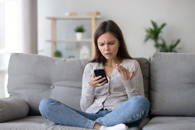 en kvinna sitter i en soffa med sin mobiltelefon